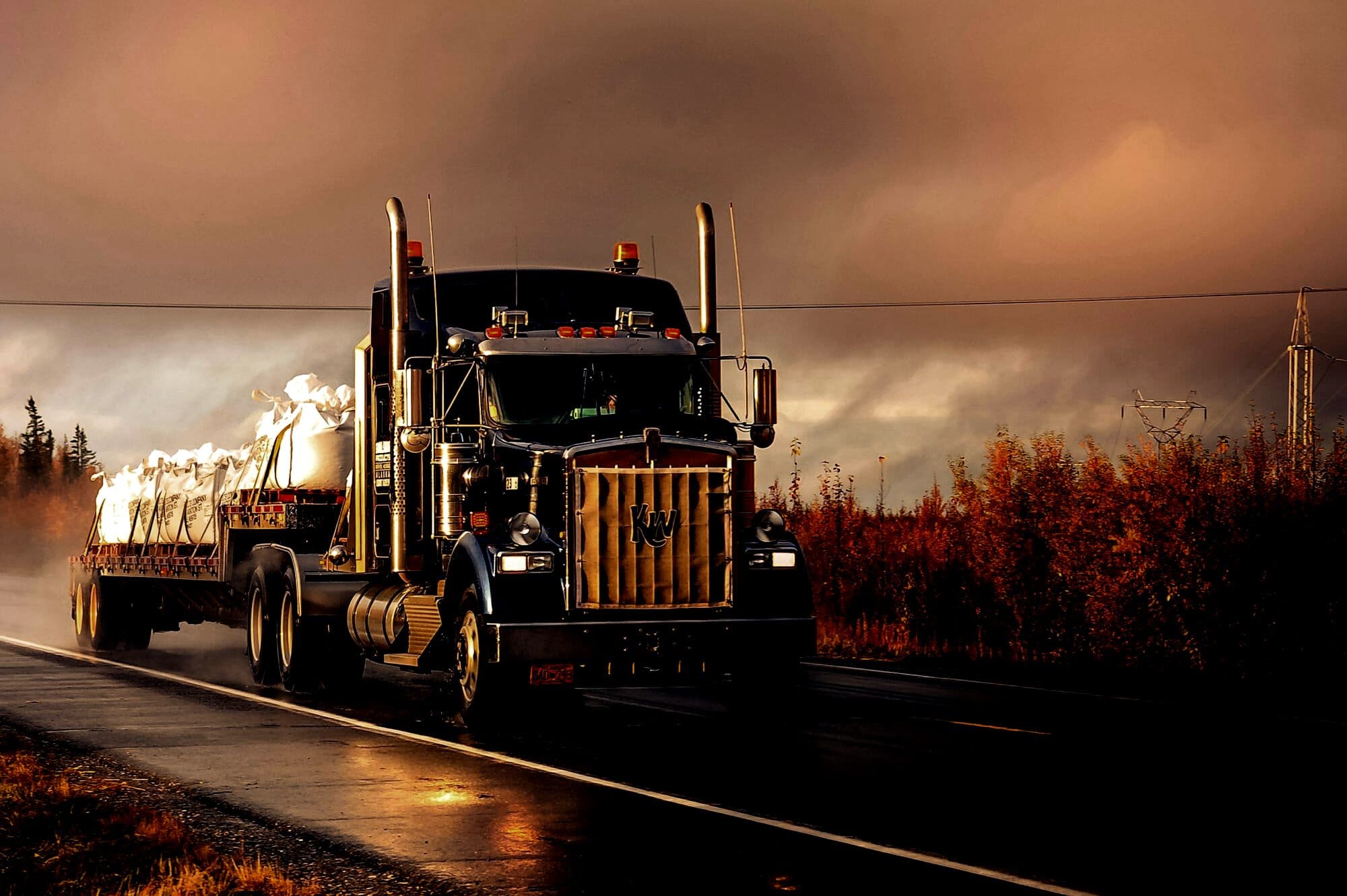 Working American tractor on a wet two-lane road
